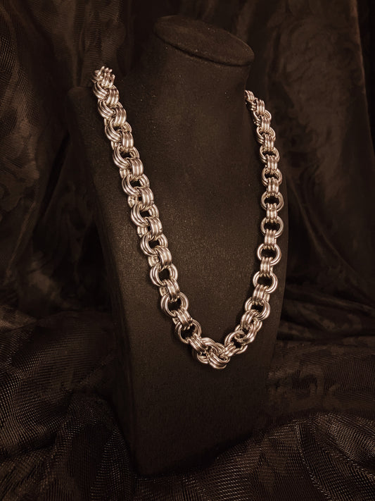 Silver chain necklace on a black mannequin against a black background