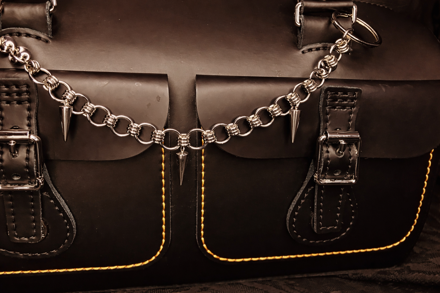 Close-up of a brown leather satchel with chain detail