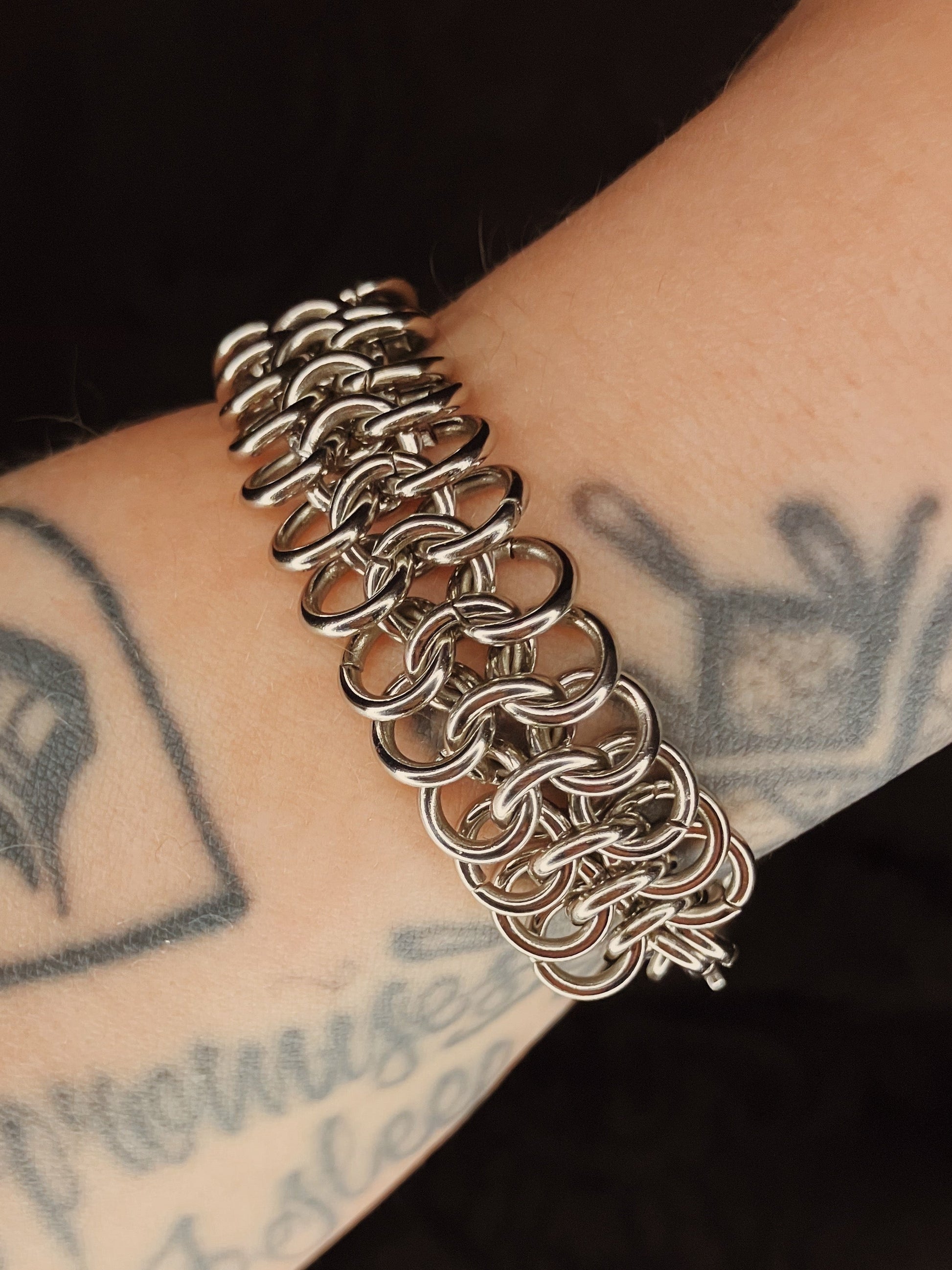 Silver chain bracelet on a wrist with tattoos