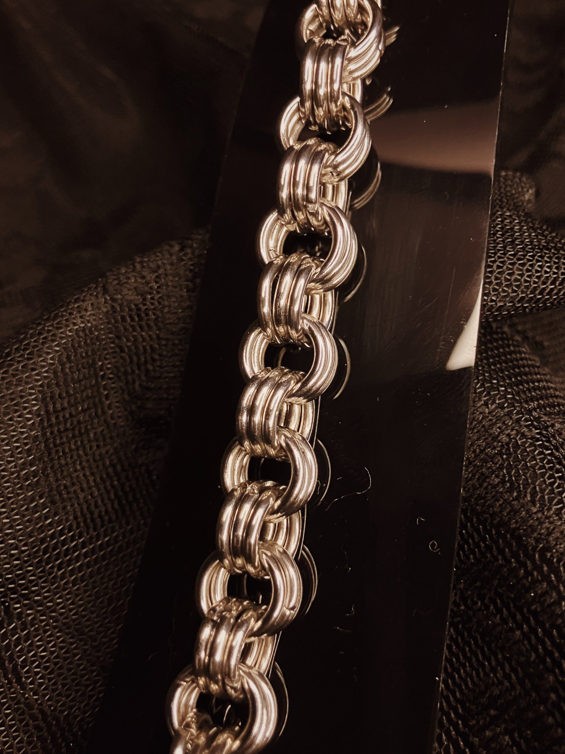 Close-up of a silver chain on a textured black background