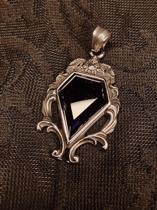 Decorative pendant with a black gemstone on a textured brown background