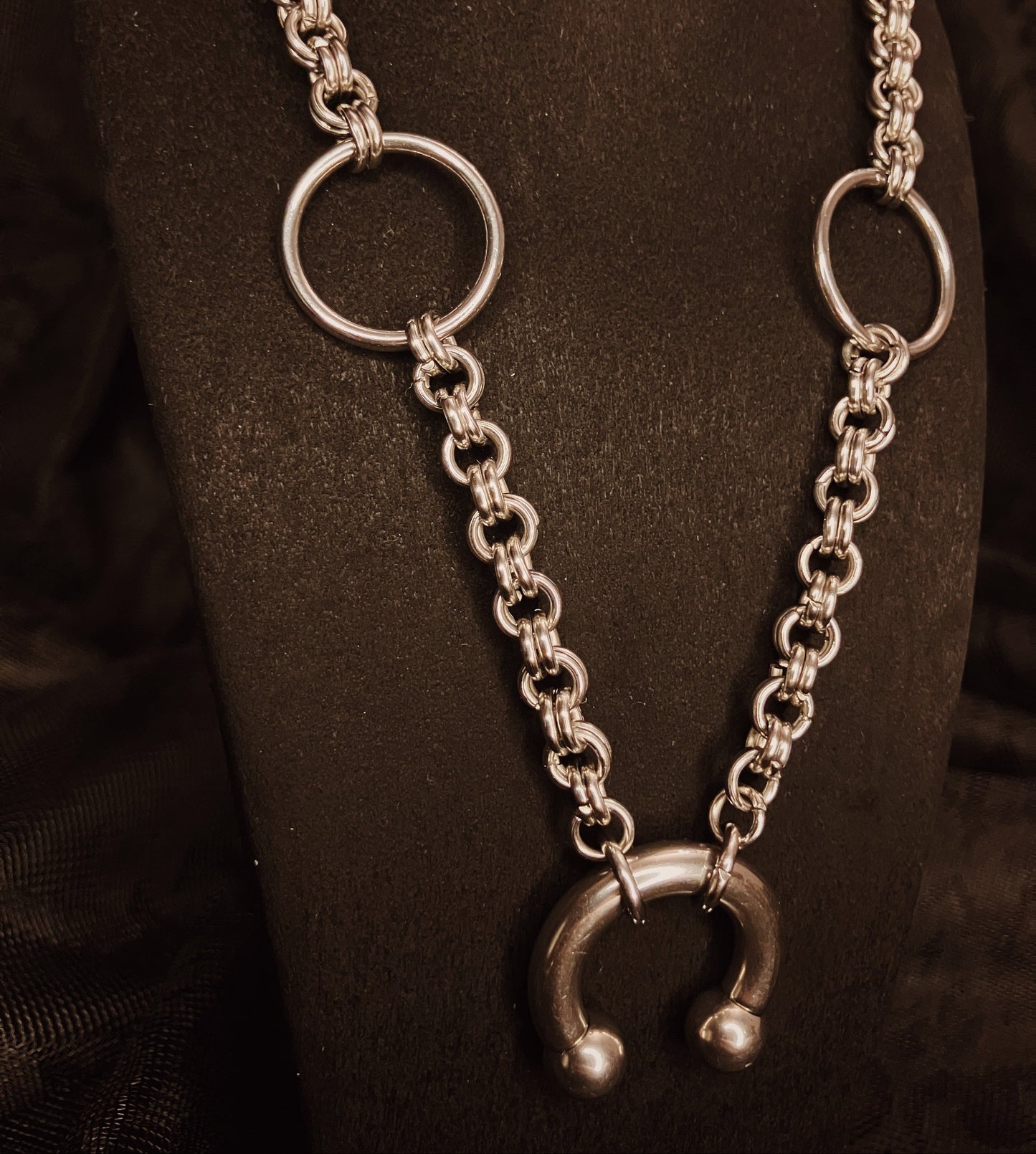 Silver chain necklace with circular links on a dark background