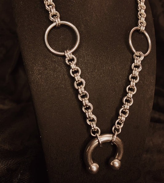 Silver chain necklace with circular links on a dark background