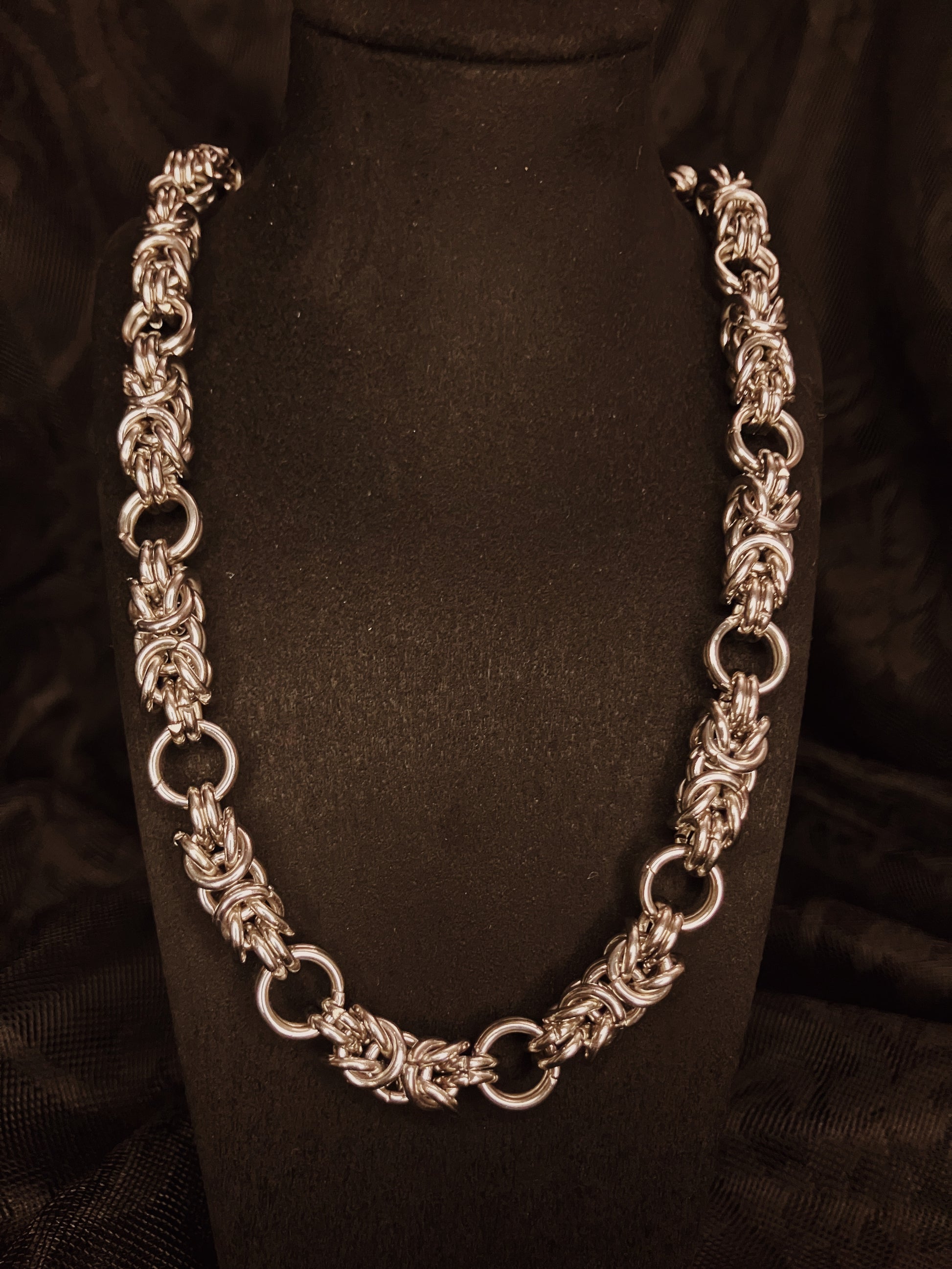 Silver chain necklace on a black mannequin against a black background