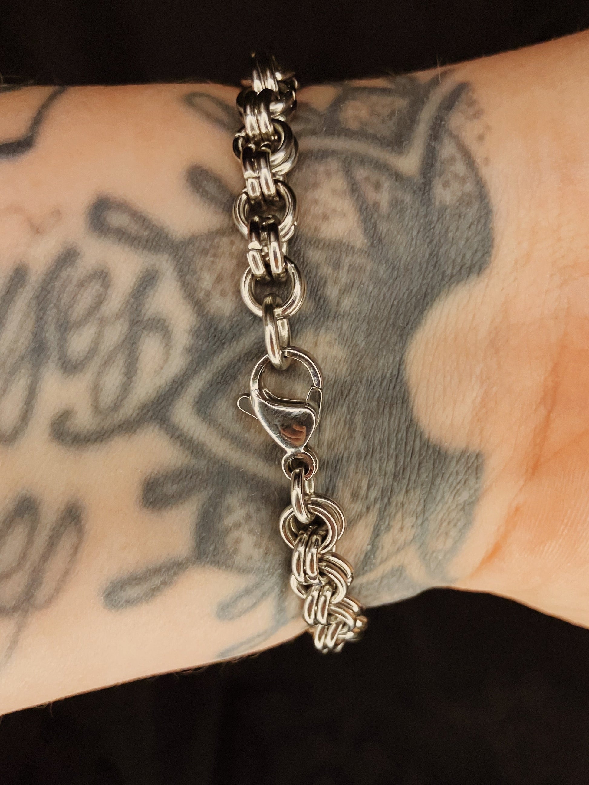 Silver chain bracelet on a wrist with tattoos