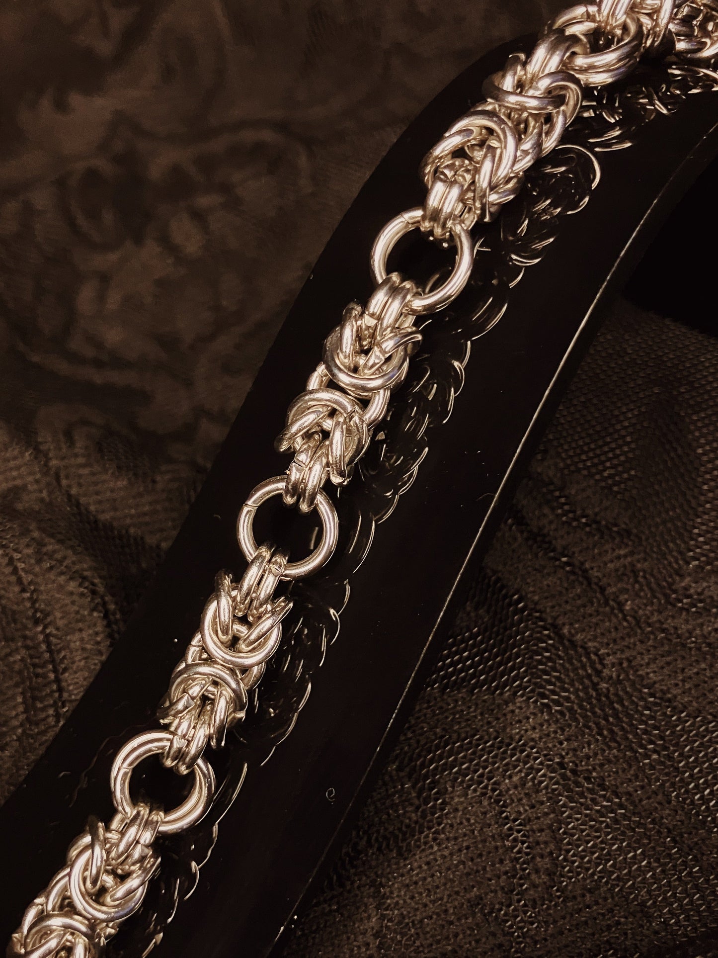 Silver chain bracelet on a textured brown background