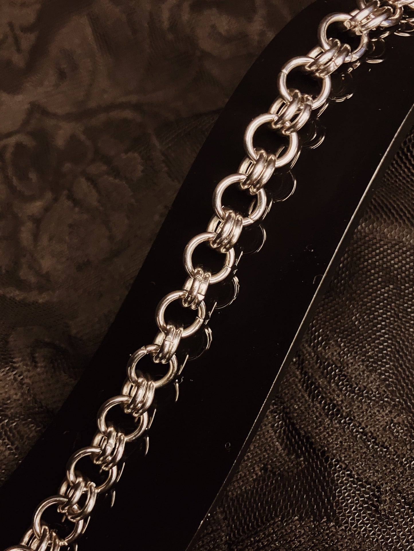 Silver chain bracelet on a textured brown surface