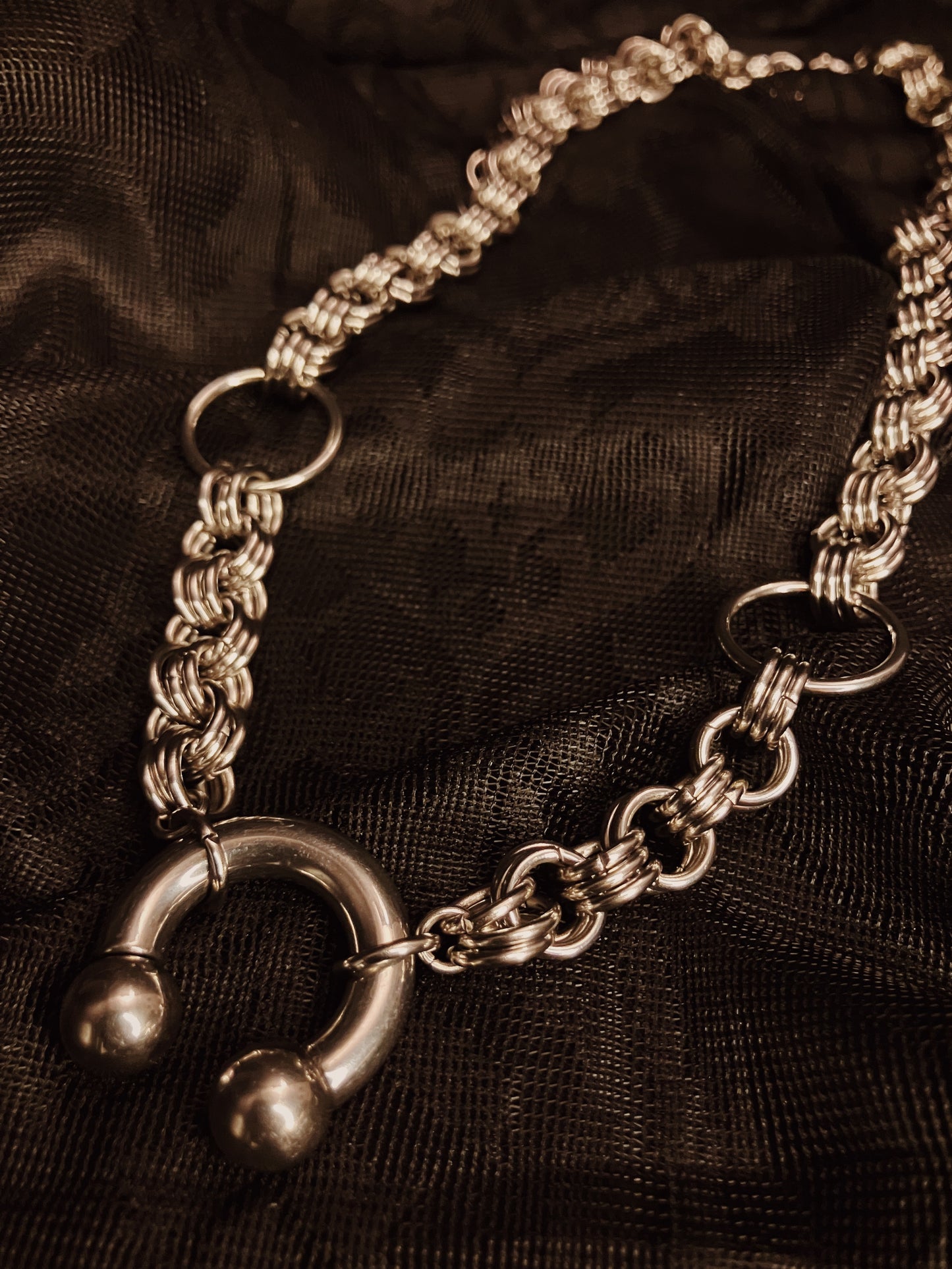 Silver chain necklace on a dark fabric background
