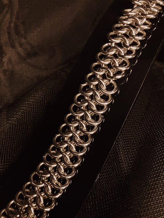 Close-up of a silver chain bracelet on a dark fabric background
