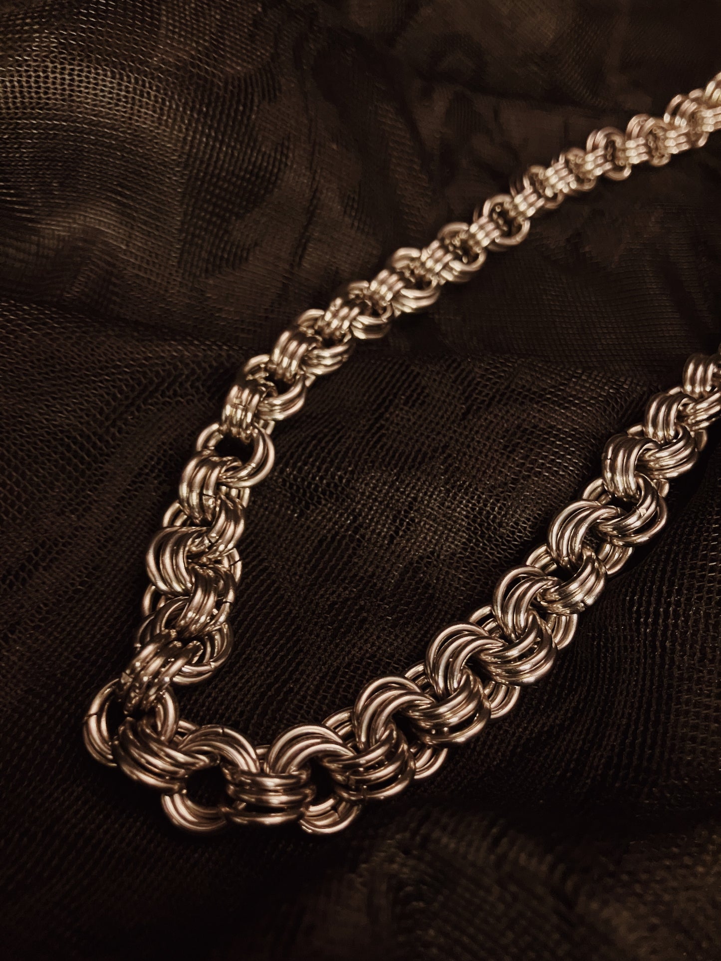 Silver chain necklace on a black textured background