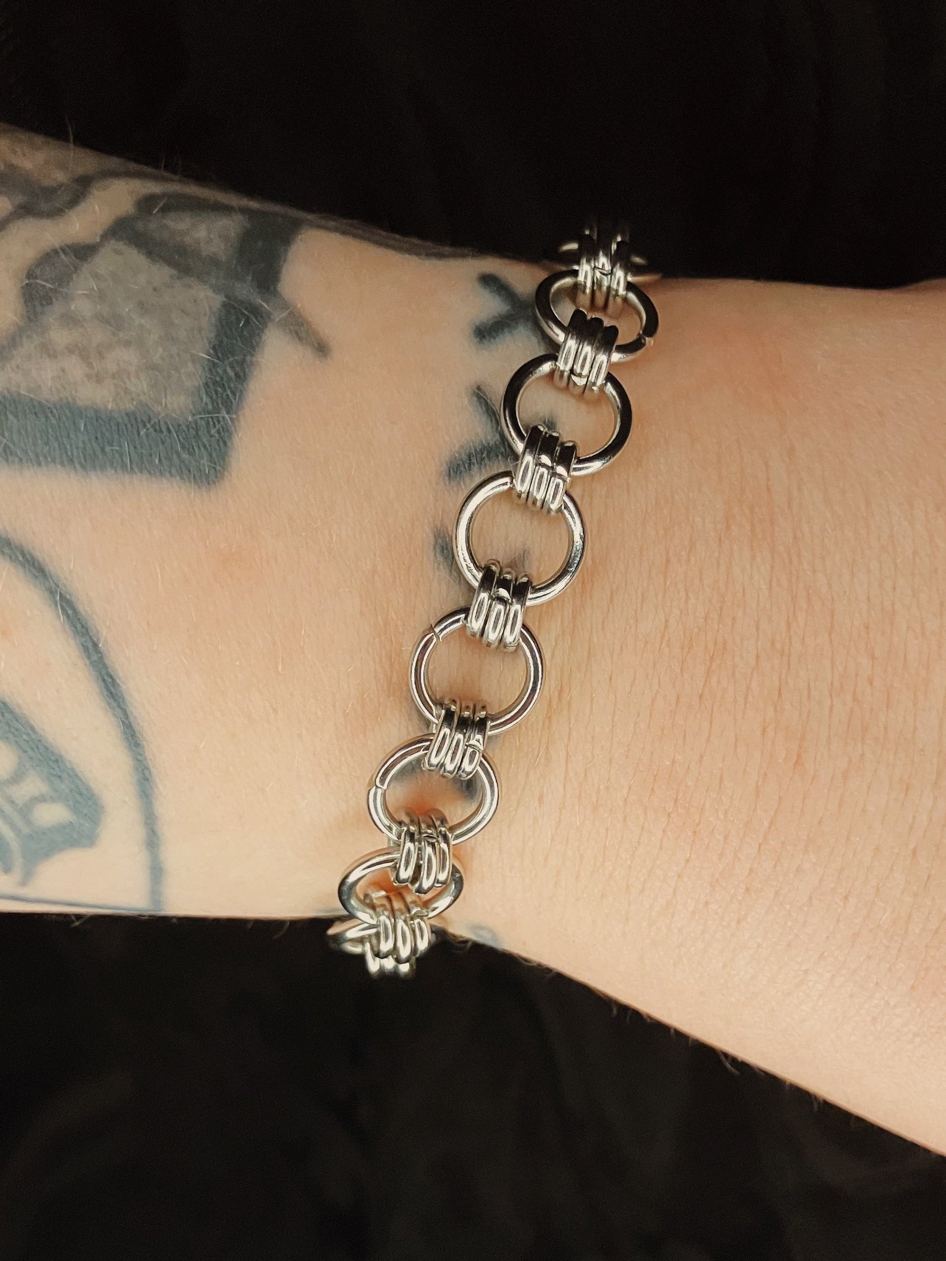 Silver chain bracelet on a wrist with tattoos