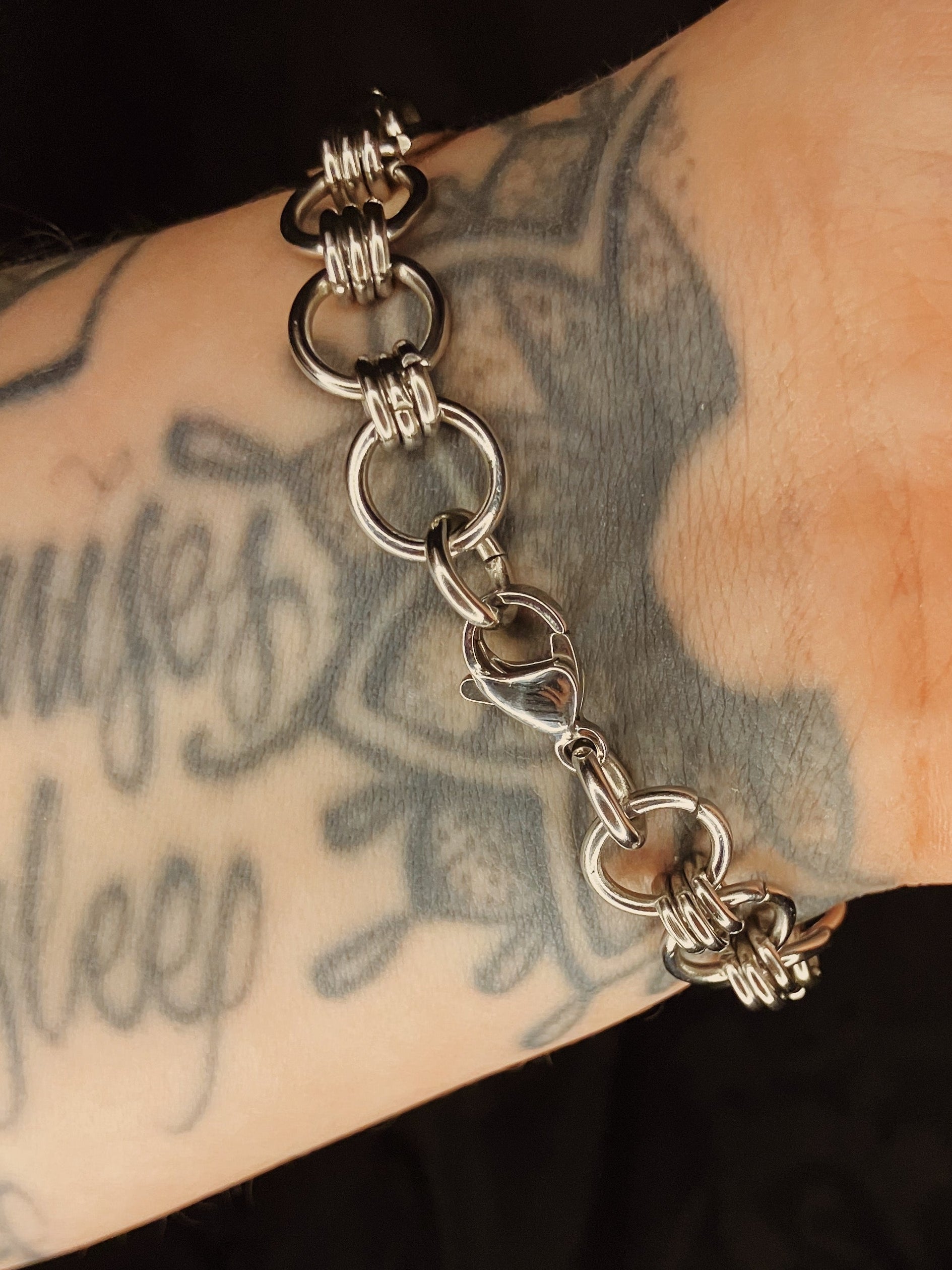 Silver chain bracelet on a tattooed arm
