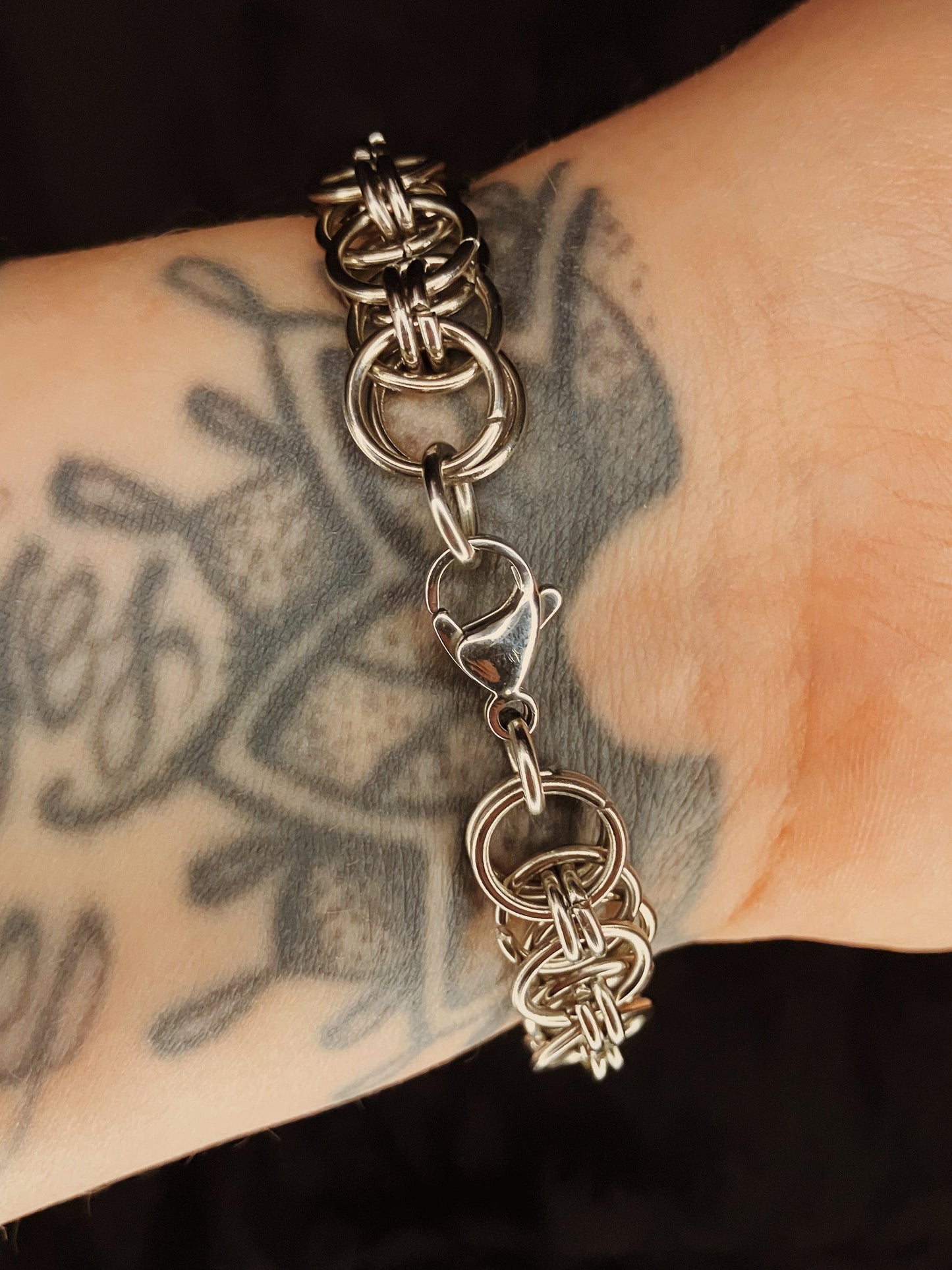 Metal chain bracelet on a wrist with tattoos