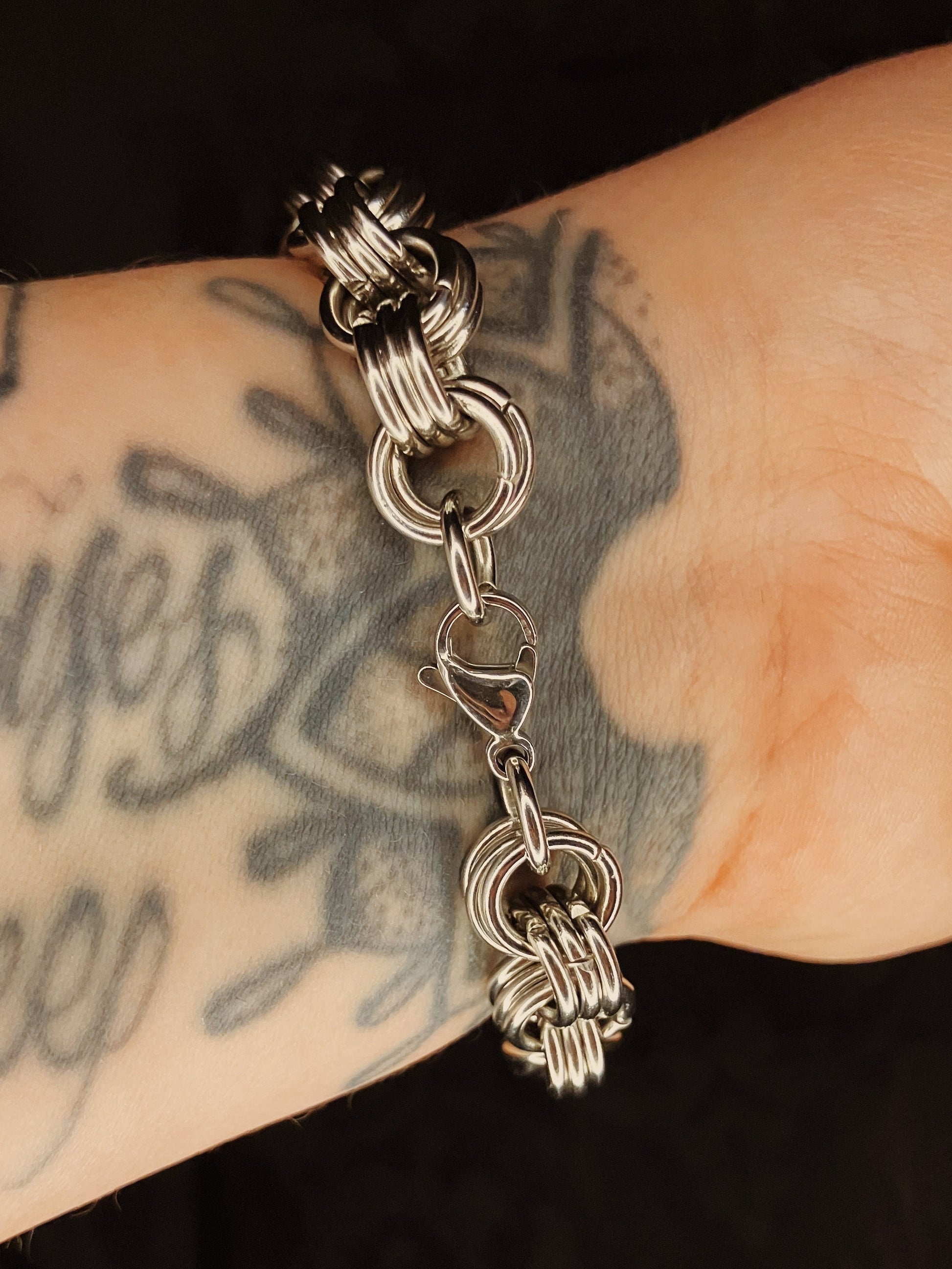Silver bracelet  on a wrist with tattoos