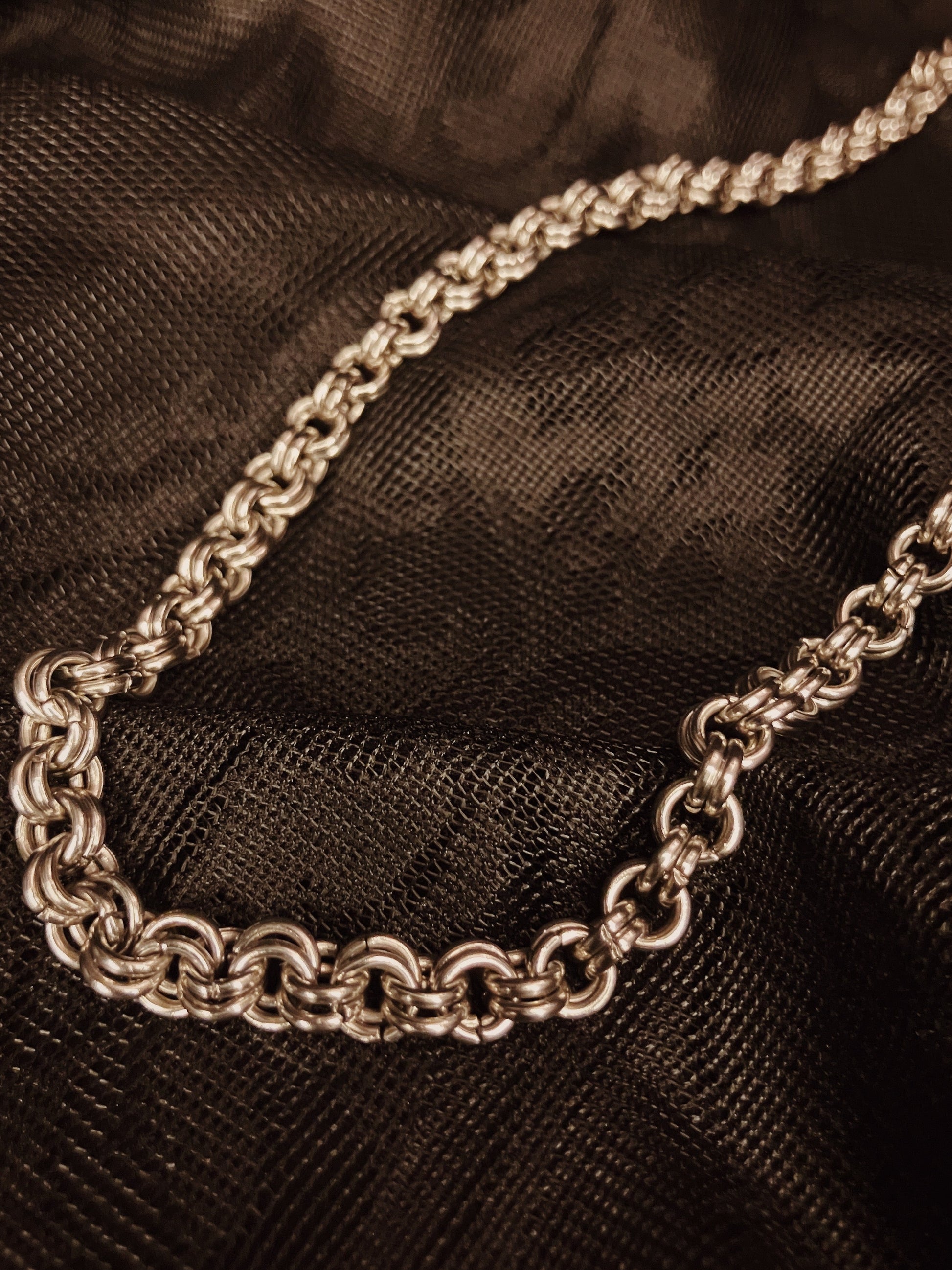 Silver chain necklace on a dark fabric background