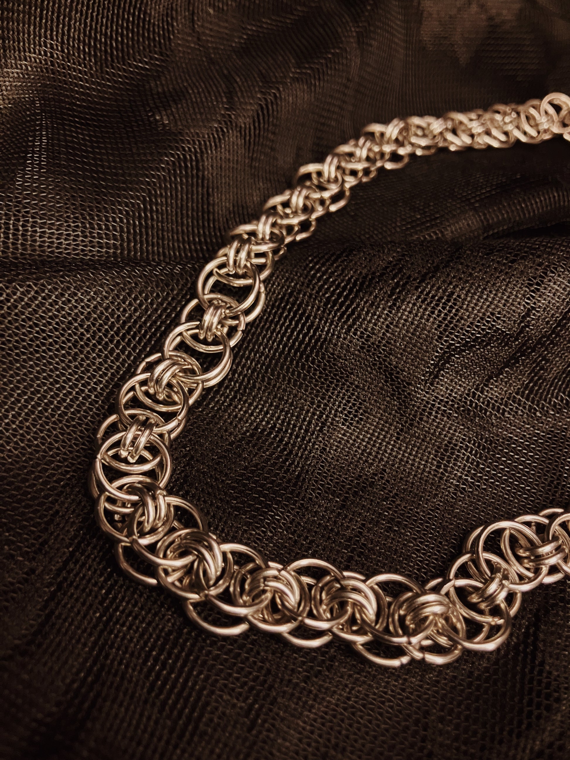 Silver chain necklace on a black textured fabric background