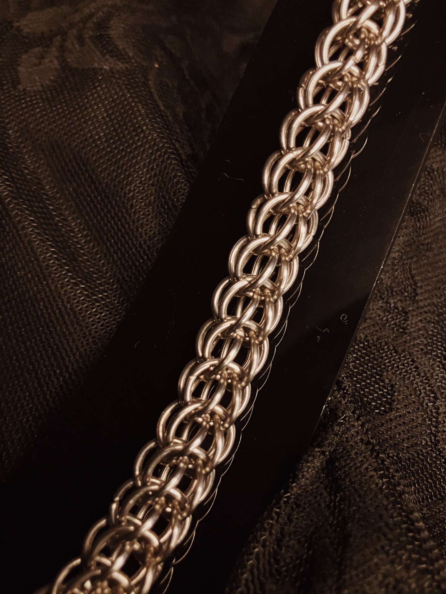 Close-up of a silver chain on a dark textured fabric background