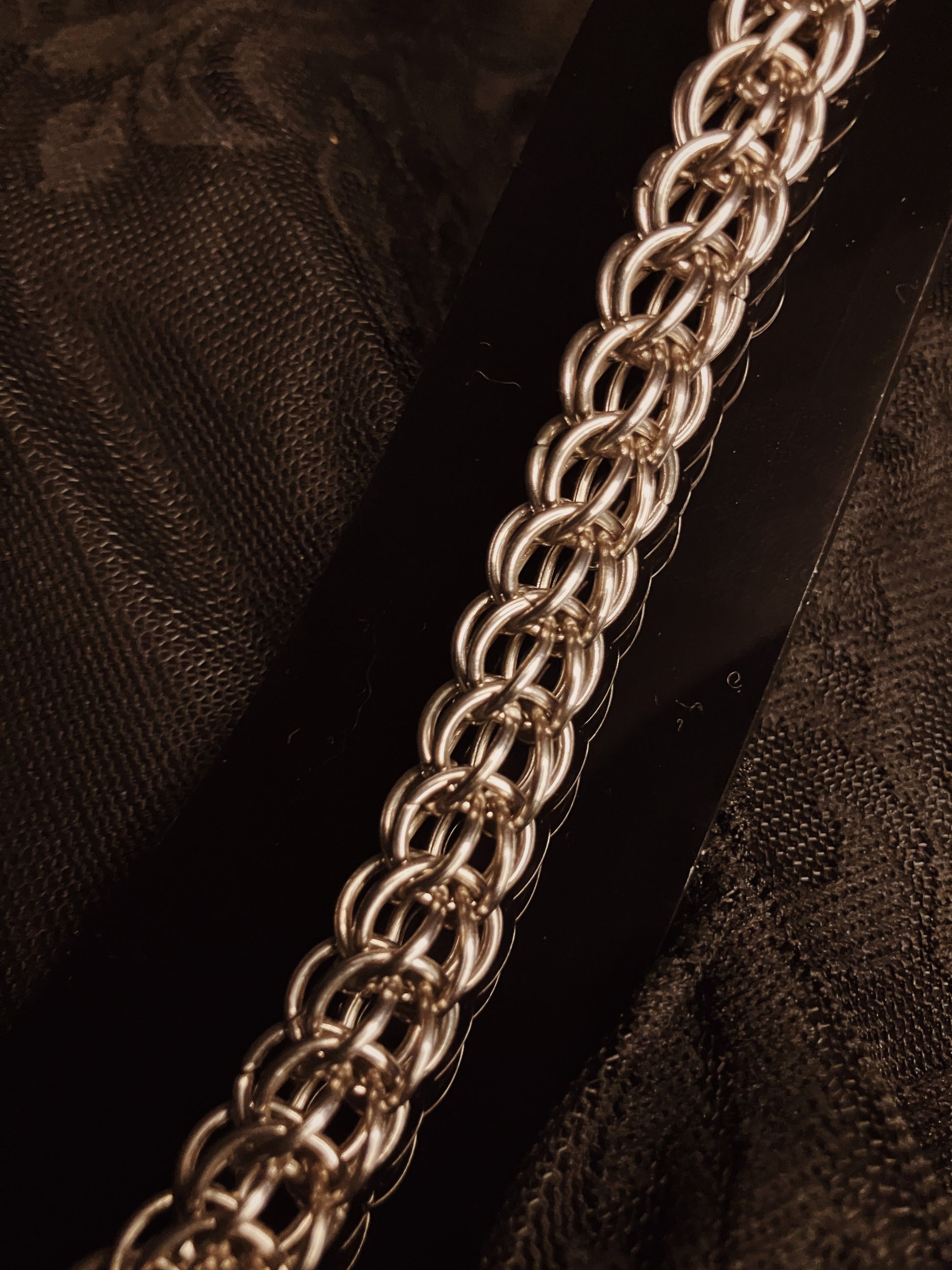 Close-up of a silver chain on a dark textured fabric background