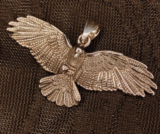 stainless steel crow flying emblem on a textured brown fabric background