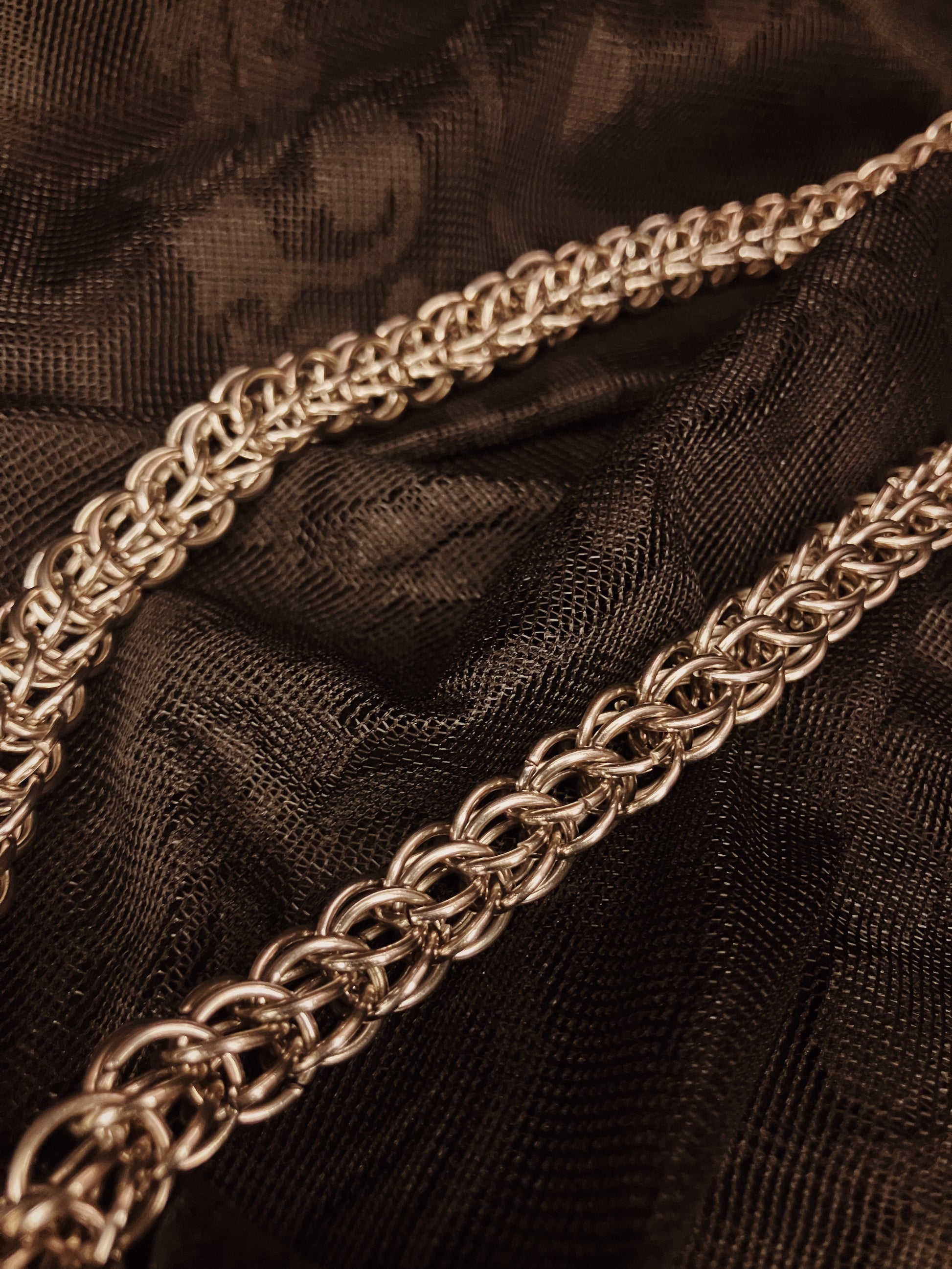 Close-up of gold chain belt on black fabric background