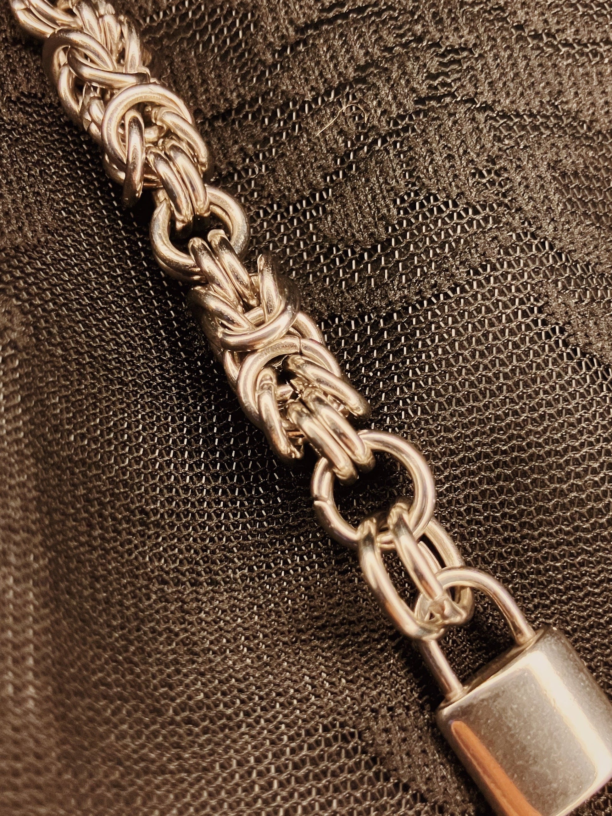 Close-up of a silver chain with a lock on a textured brown background