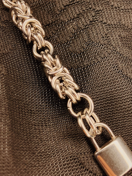 Close-up of a silver chain with a lock on a textured brown background