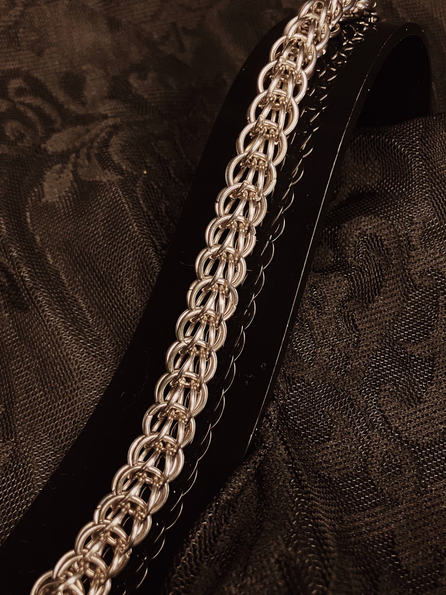 Silver chain bracelet on a black textured fabric background