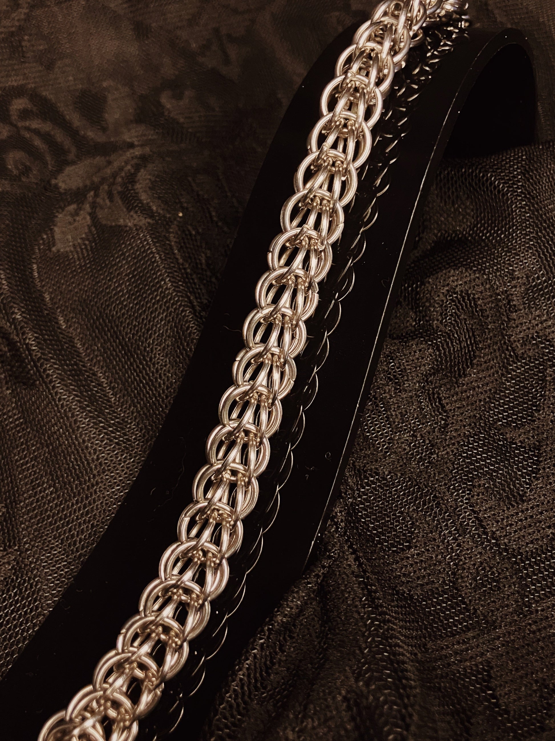Silver chain bracelet on a black textured fabric background