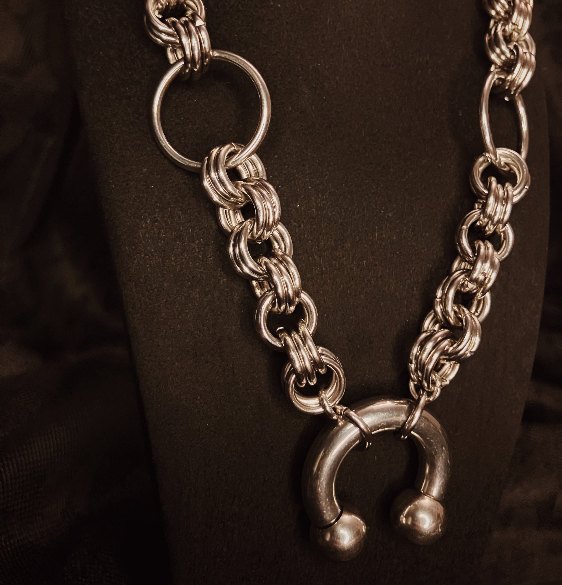Silver chain necklace with a unique clasp on a dark background